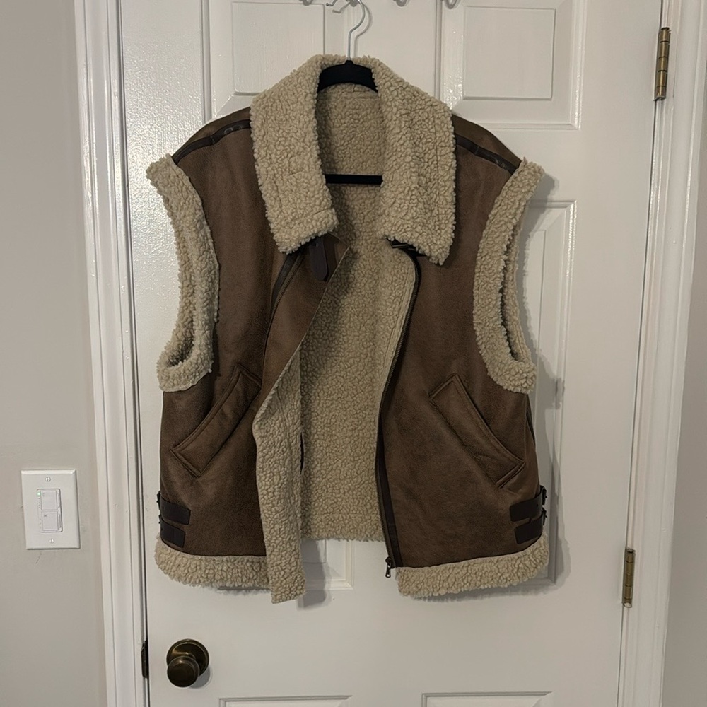 Oversized brown vest with cozy lining. Buckle hardware around collar.